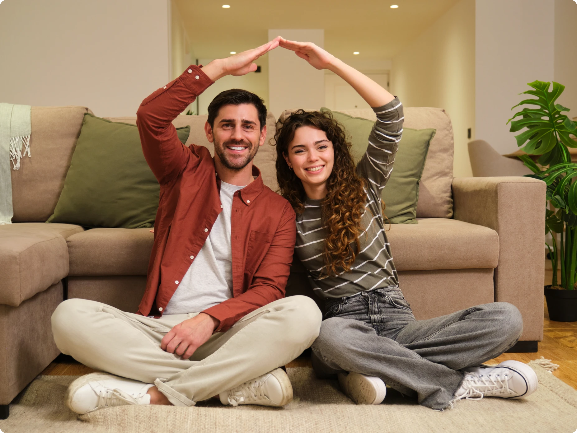 Smiling pair making home gesture indoors
